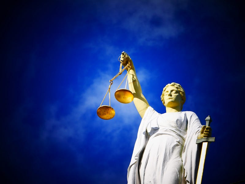 A statue of Lady Justice balancing scales against a dark blue sky.