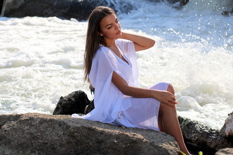 Beautiful woman sitting on rock by rapids.