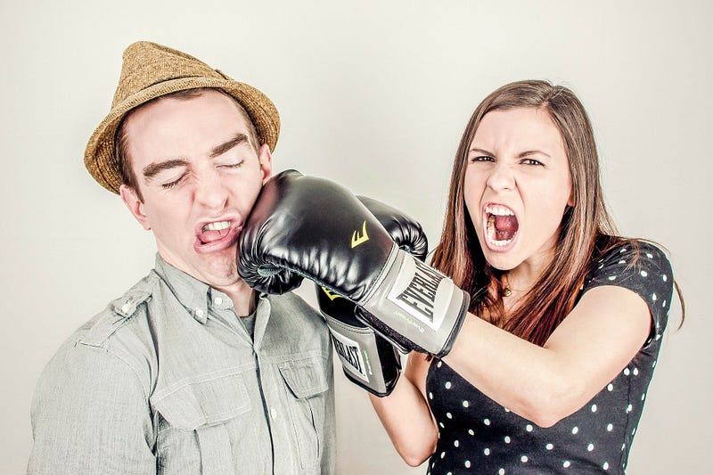 Comical picture of woman with boxing glove punching man in jaw.